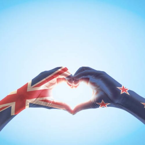 New Zealand flag pattern on people hands in heart shaped isolated on blue sky  for NZ national public holiday celebration